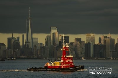 A tug boat sails past Manhattan at sundown. October 2019.